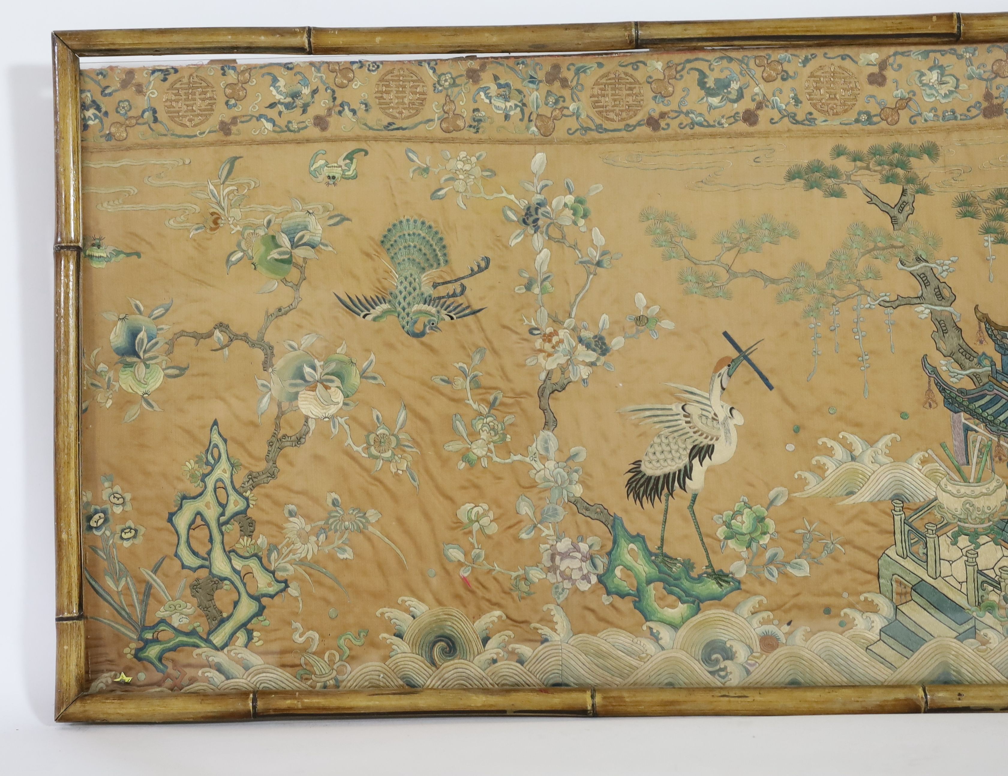 A Chinese apricot ground embroidered silk table frontal, late Qing dynasty, 58cm x 178cm, now trimmed and framed